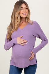 woman wearing a lavender v-neck maternity top and holding her baby bump
