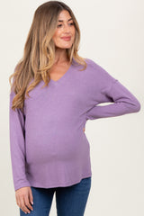 woman wearing a lavender v-neck maternity top that comfortably accommodates a baby bump