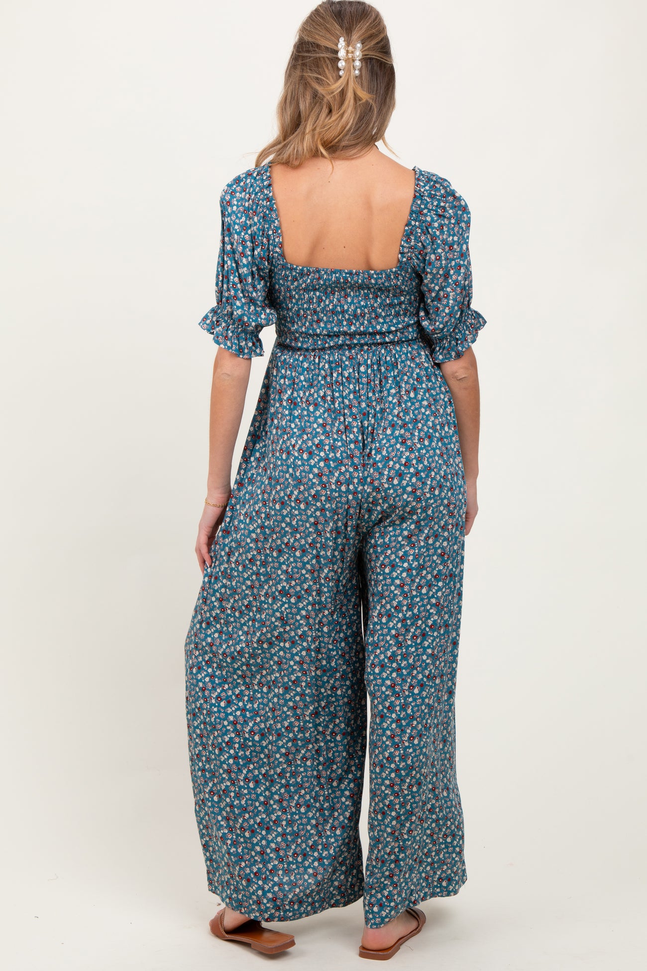 woman wearing a floral maternity jumpsuit with a backless design and short ruffled sleeves