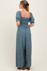 woman wearing a navy blue floral smocked maxi dress with puff sleeves, shown from the back