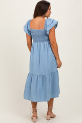 woman wearing a light blue maternity dress with ruffled sleeves and a smocked bodice, showing her back