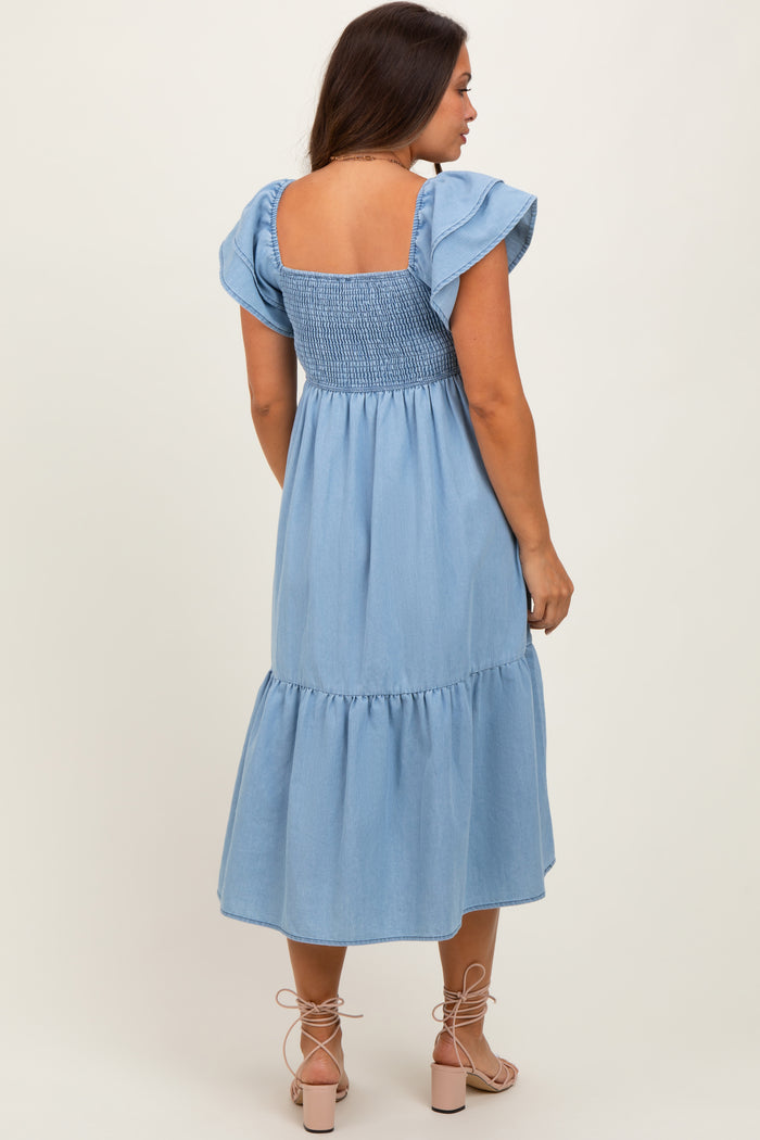 woman wearing a light blue maternity dress with ruffled sleeves and a smocked bodice, showing her back
