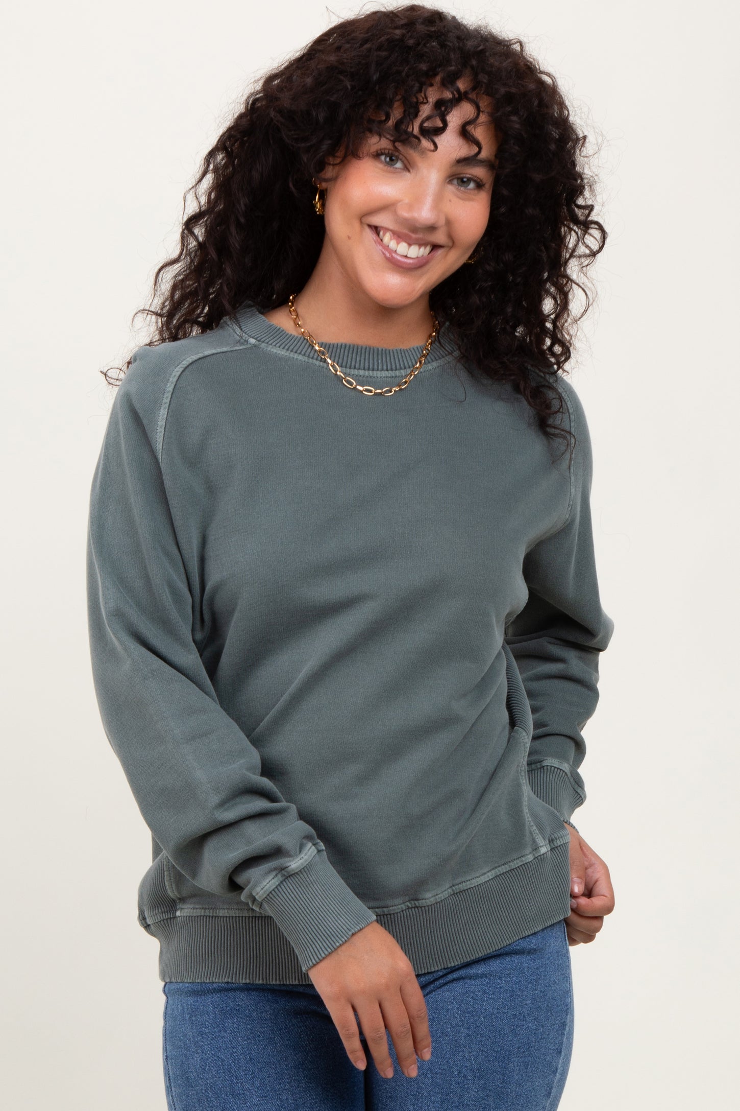 woman wearing a green oversized sweatshirt with long sleeves and a relaxed fit