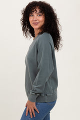 woman wearing a green long sleeve sweatshirt with ribbed cuffs and hem, styled with blue jeans