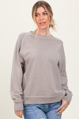 woman wearing a light gray oversized sweatshirt with ribbed cuffs and hem, styled with blue jeans