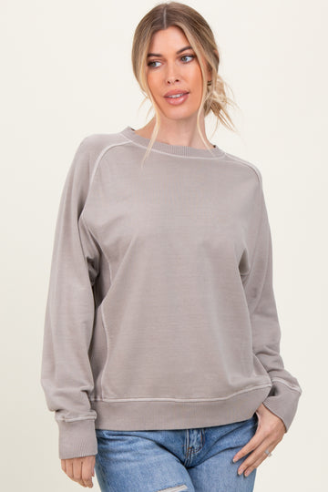 woman wearing a light gray oversized sweatshirt with ribbed cuffs and hem, styled with blue jeans