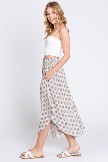 woman wearing a white cropped tank top and a flowy patterned maxi skirt with a side slit