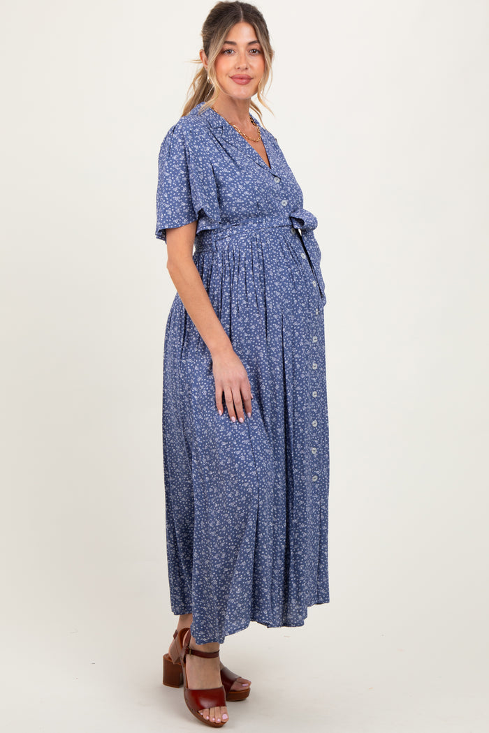 woman wearing a blue floral maternity maxi dress with a tie waist and buttons, showcasing her baby bump