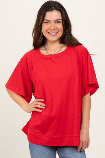 woman wearing a bright red oversized t-shirt with short sleeves and relaxed fit, standing and smiling