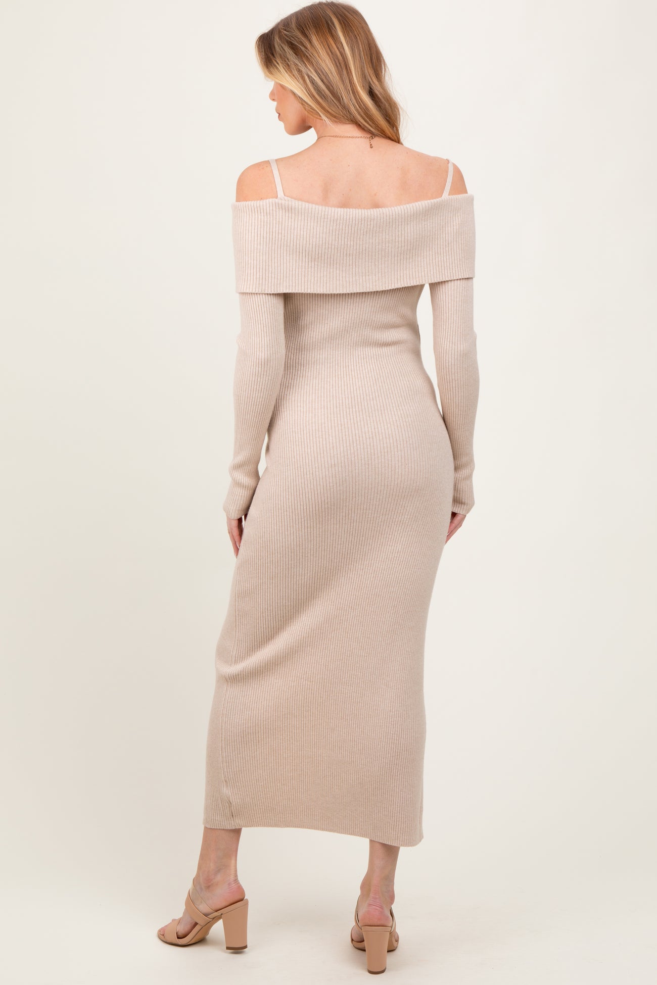 woman wearing a light beige off-shoulder maternity dress with long sleeves and a fitted silhouette