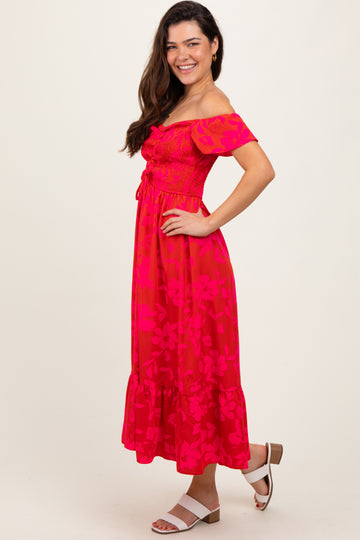 woman wearing a bright pink off-the-shoulder maxi dress with floral pattern and ruffled hem, posing sideways