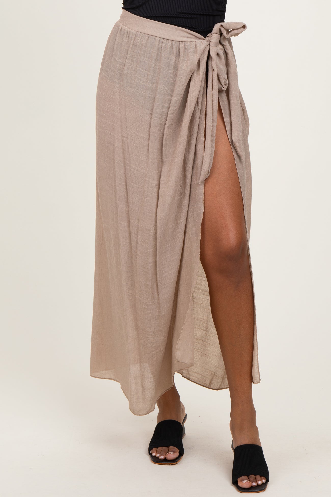 woman wearing a beige maxi skirt with a side slit and tie detail at the waist