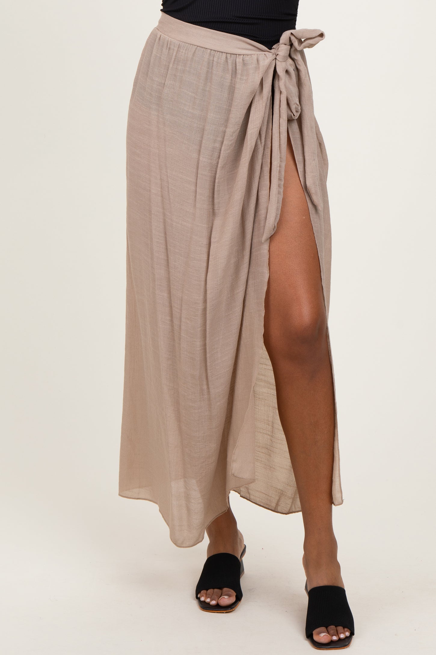 woman wearing a beige maxi skirt with a side slit and tie detail at the waist