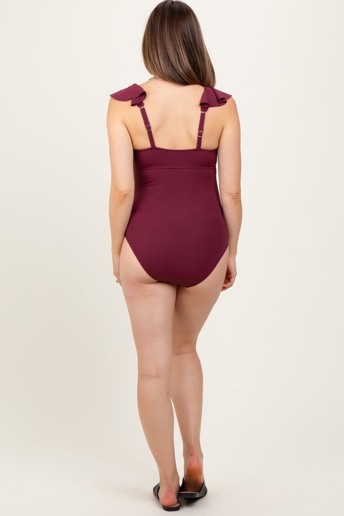 woman wearing a burgundy ribbed one-piece maternity swimsuit with ruffled straps and a low back, no visible baby bump
