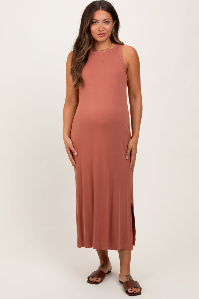 woman wearing a rust-colored sleeveless maternity dress with side slits and a visible baby bump