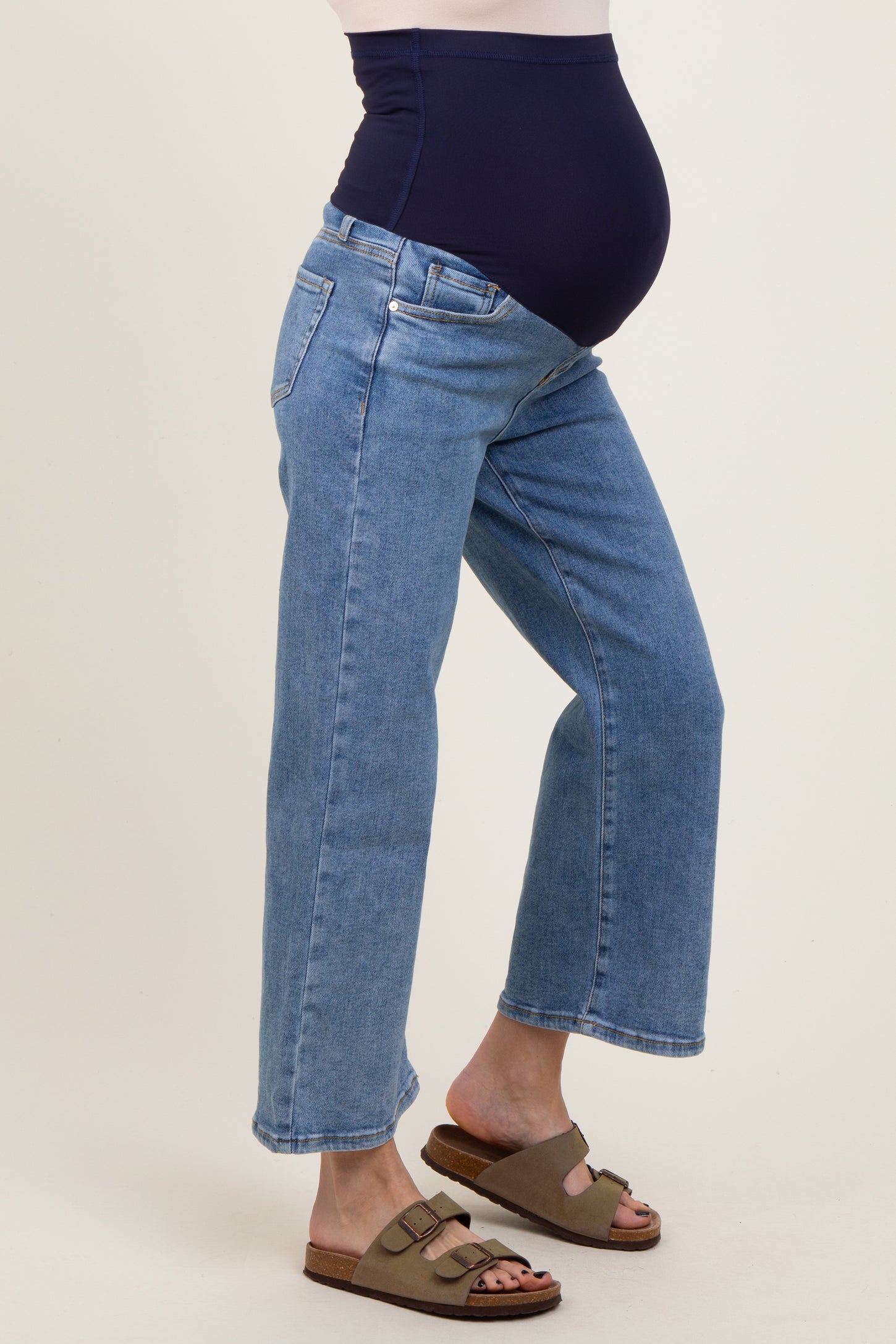 woman wearing a pair of light blue maternity jeans with a navy blue belly panel and comfortable sandals