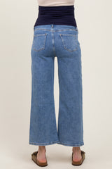 woman wearing light blue maternity wide-leg jeans, viewed from the back, with a fitted top and flat sandals