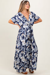 woman wearing a navy floral print maternity maxi dress with a tie front detail and short sleeves