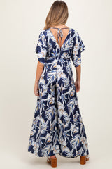 woman wearing a navy floral print maternity maxi dress with flutter sleeves and an open back