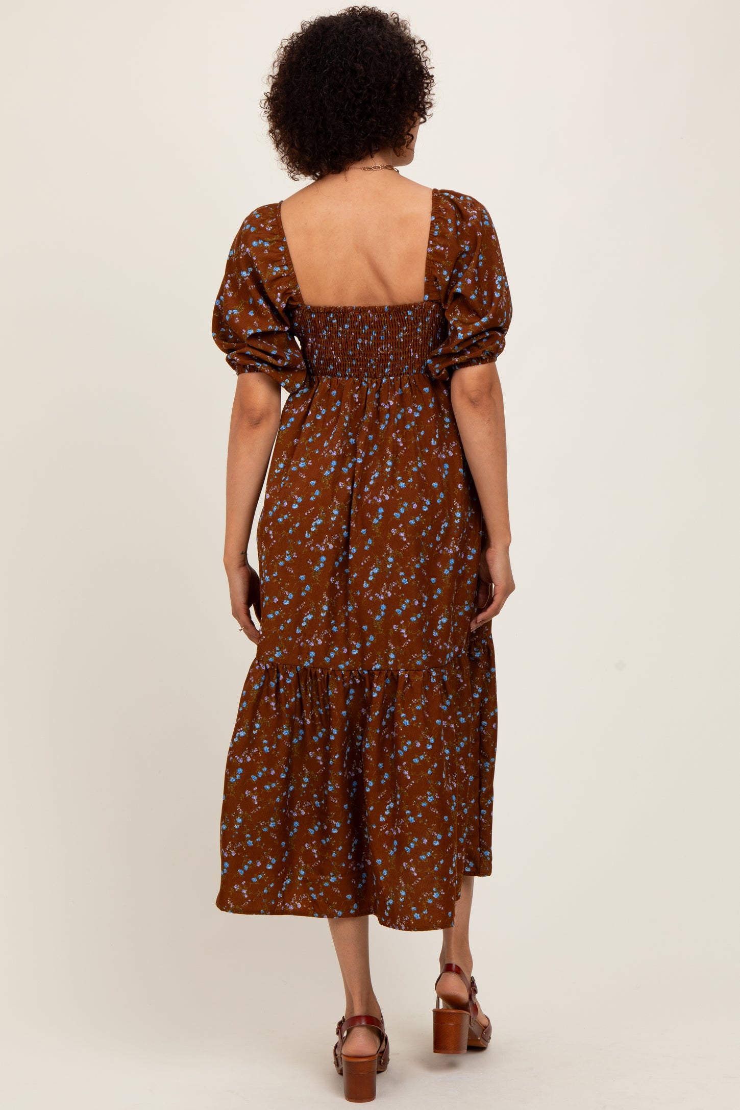 woman wearing a brown floral midi dress with puff sleeves and a square back neckline, seen from the back