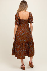 woman wearing a brown floral maternity dress with a smocked back and tiered skirt, showing a baby bump