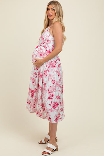 woman wearing a floral maternity dress with pink and white colors, holding her baby bump