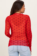 woman wearing a red sheer maternity top with black heart polka dots and long sleeves, seen from the back