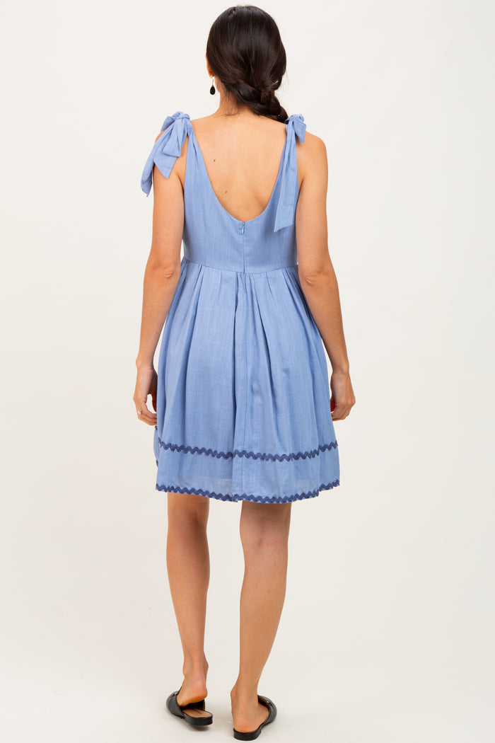 woman wearing a back view of a light blue sundress with tie straps and scalloped hem details