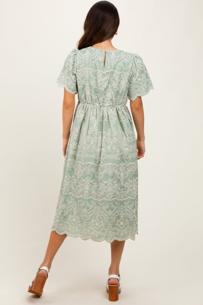woman wearing a mint green lace midi dress with short sleeves and a cinched waist, showing the back view
