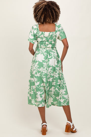 woman wearing a green floral maternity dress with short sleeves and a square back, showcasing a comfortable fit