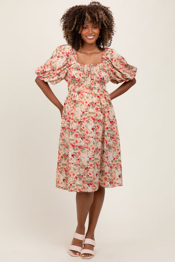 woman wearing a floral puff sleeve maternity dress with a fitted bodice and flowy skirt, baby bump visible