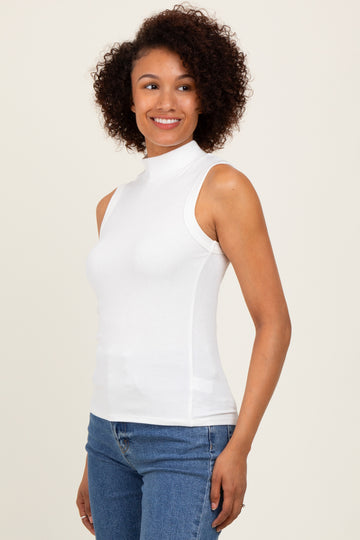 woman wearing a white sleeveless mock neck top paired with blue jeans