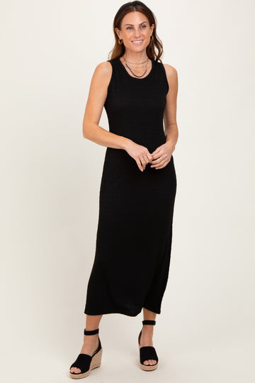 woman wearing a black sleeveless maxi dress with a ribbed texture and standing in wedge sandals