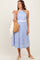 woman wearing a blue and white striped halter neck sundress and holding a straw bag