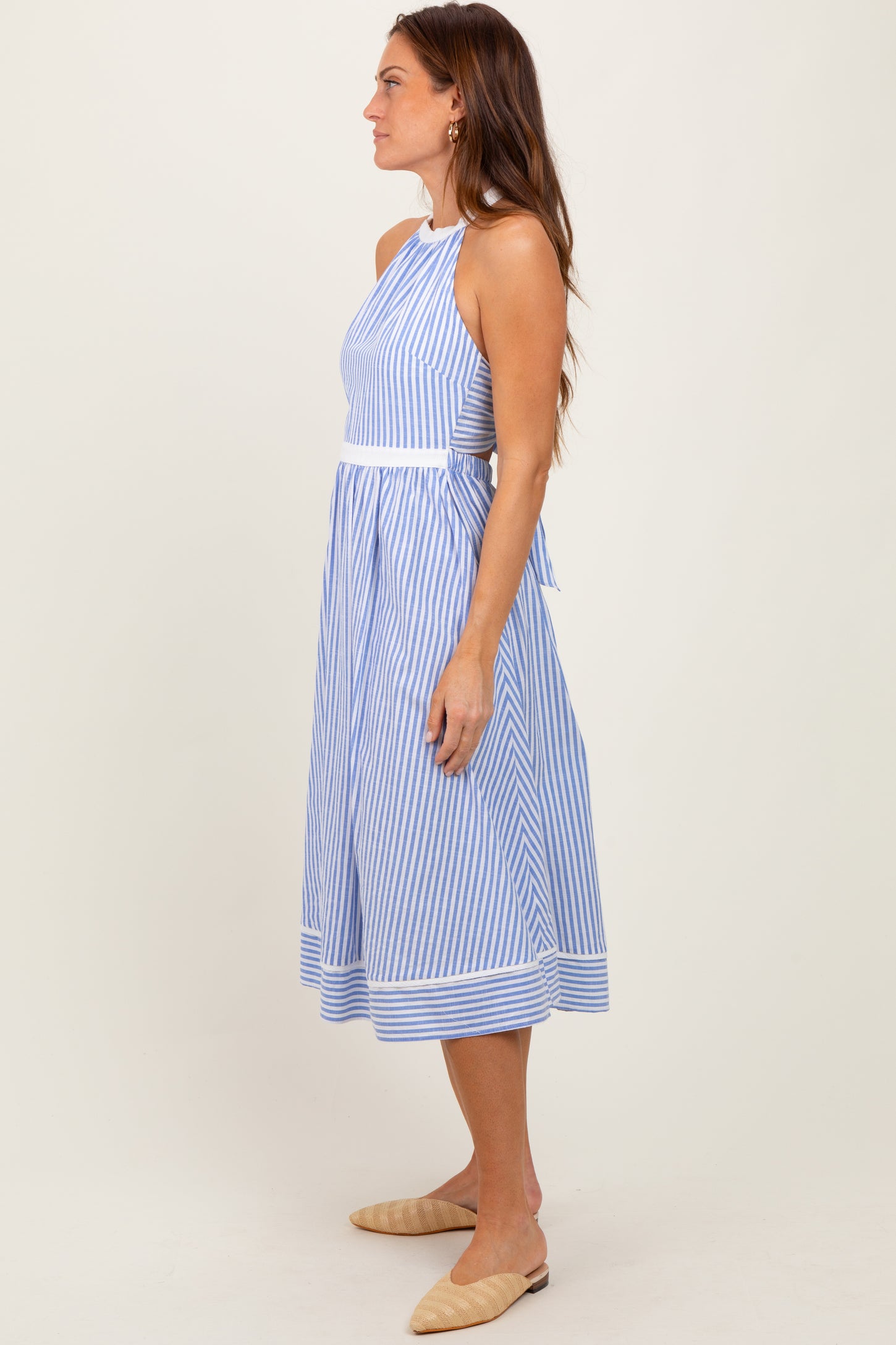 woman wearing a blue and white striped halter neck midi dress with a fitted bodice and a flowing skirt