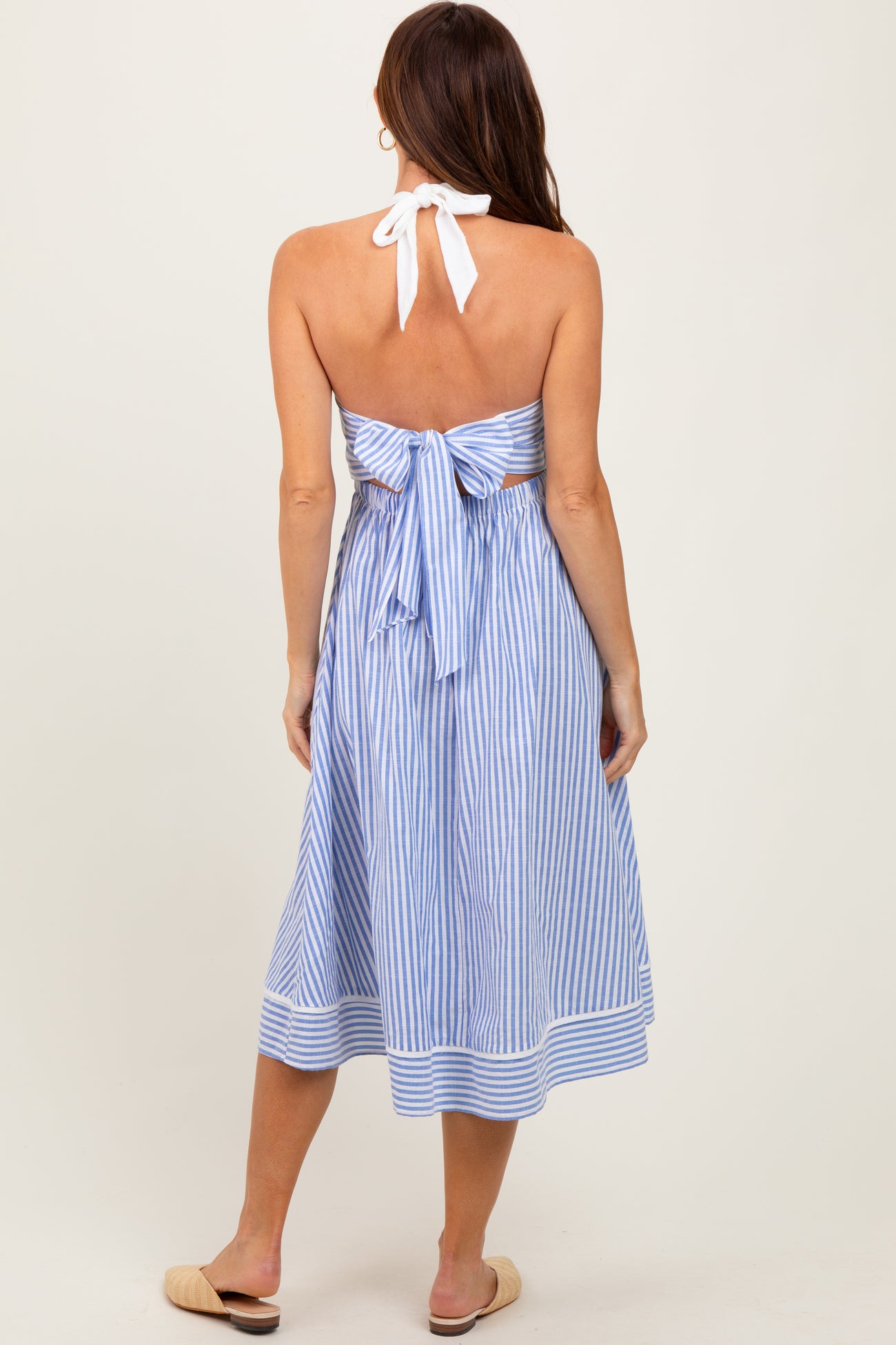 woman wearing a blue and white striped halter neck dress with a tied back detail and a midi length, shown from the back