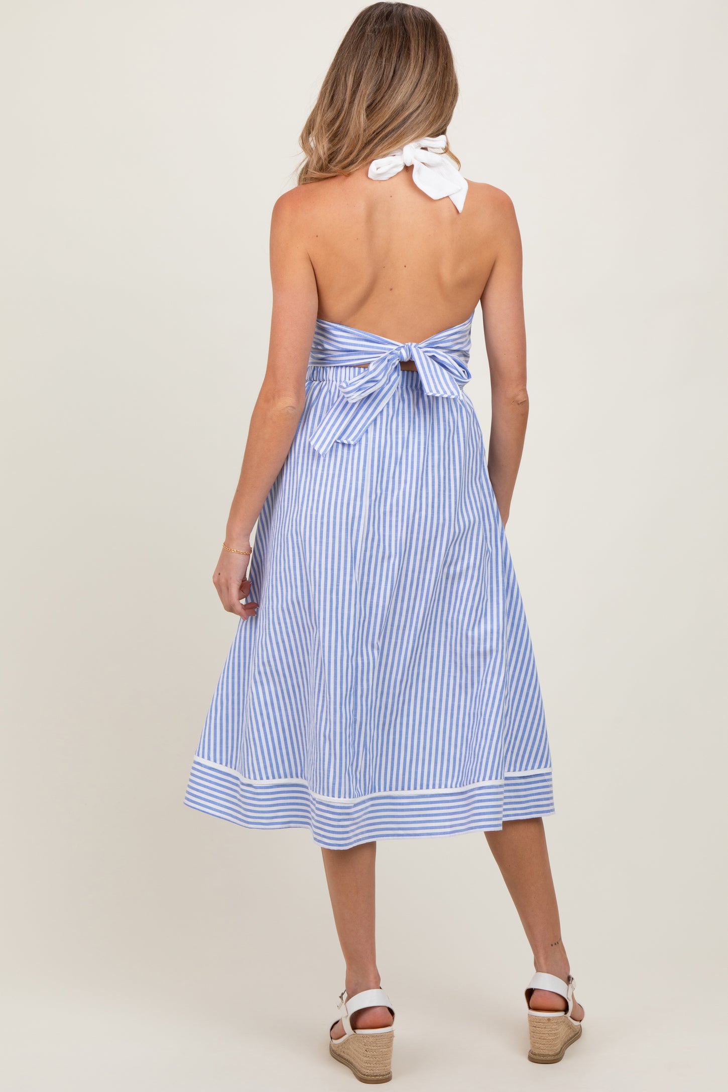 woman wearing a blue and white striped maternity midi dress with a tied back and spaghetti straps
