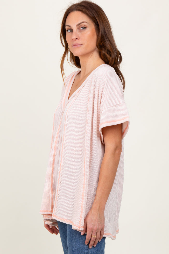 woman wearing a light pink and white striped short sleeve tunic top with a v-neckline and relaxed fit
