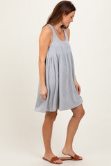 woman wearing a gray and white striped sleeveless swing dress and brown slide sandals