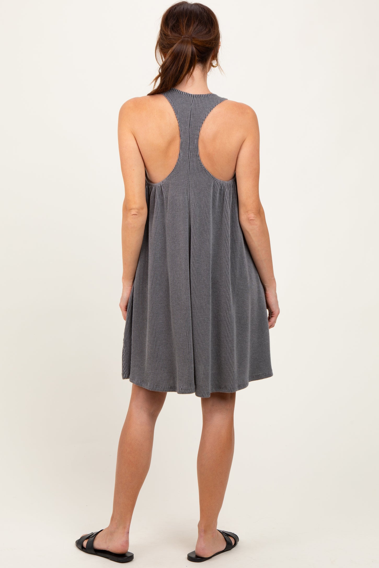 woman wearing a gray stripe sleeveless dress with a fitted bodice and flared skirt, showing an open back design