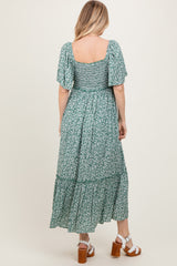 woman wearing a green floral maxi dress with short sleeves and a tiered hem, seen from the back