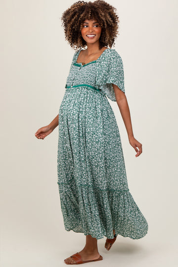 woman wearing a green floral maternity dress with short sleeves and a flowy skirt, highlighting her baby bump