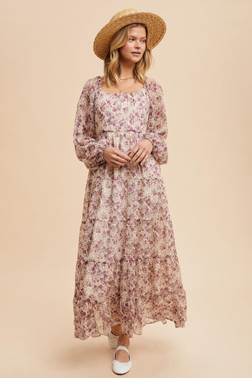 woman wearing a long floral maxi dress with long sleeves and a square neckline, paired with a straw hat