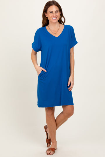 woman wearing a vibrant blue short sleeve v-neck dress with pockets, standing casually and smiling