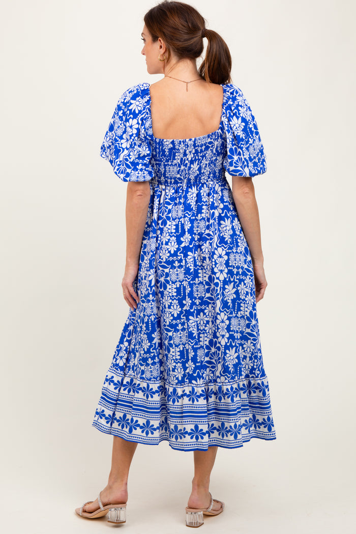 woman wearing a blue floral print midi dress with puff sleeves and a smocked bodice, showing back view