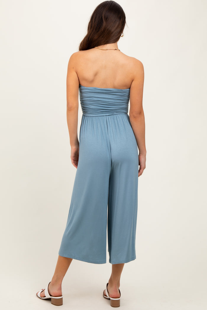 woman wearing a back view of a light blue strapless jumpsuit with a fitted bodice and wide-leg pants