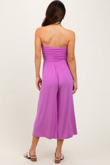 woman wearing a solid pink strapless jumpsuit with a gathered bodice and wide-leg trousers, shown from the back