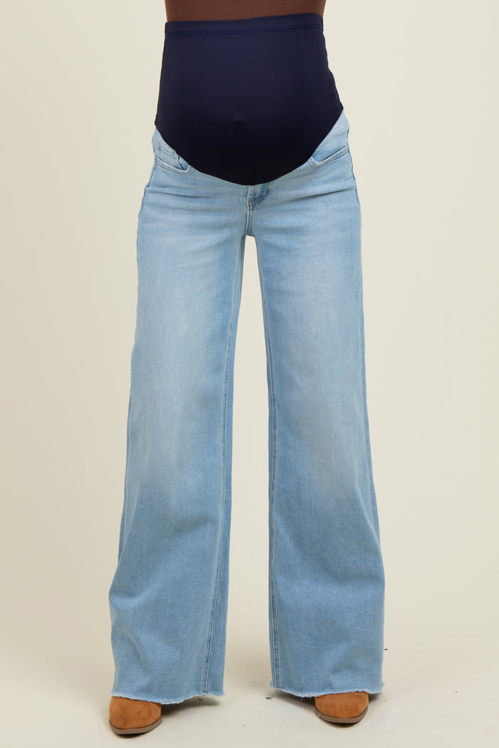woman wearing light blue maternity jeans with a navy over-the-bump waistband and flared legs