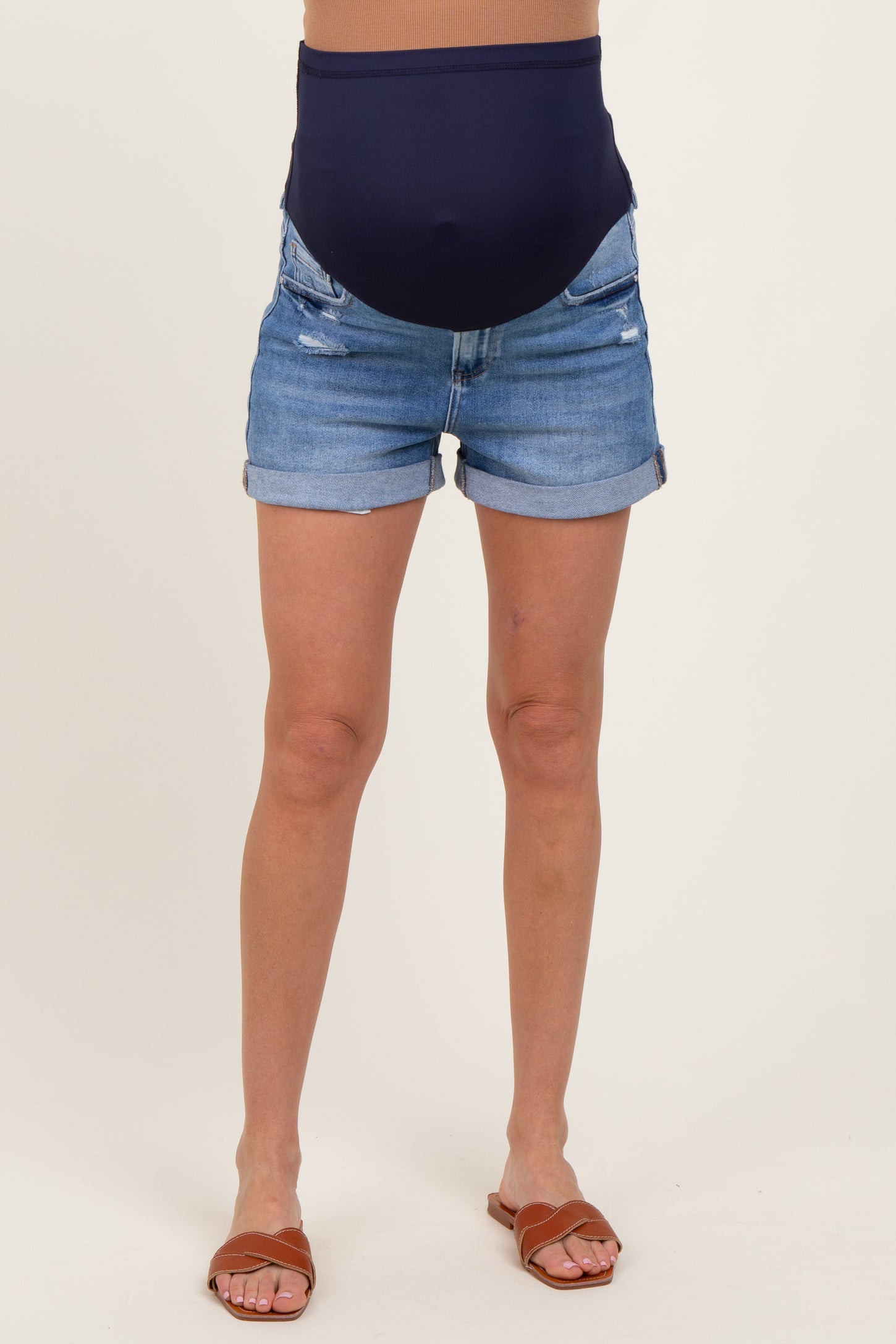 woman wearing a pair of distressed denim maternity shorts with a navy blue belly support band