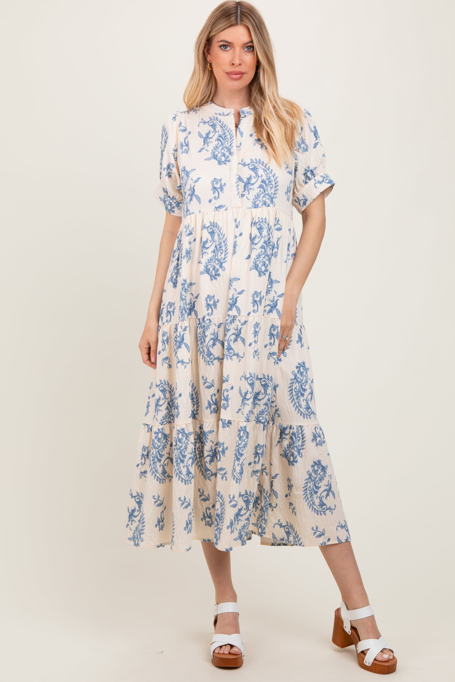 woman wearing a blue and white floral print midi dress with short sleeves and a button-up neckline